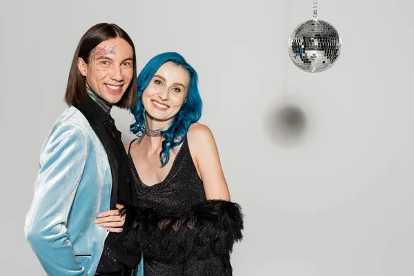 Happy queer friends in elegant festive clothes smiling at camera during christmas party on grey background — Stock Photo