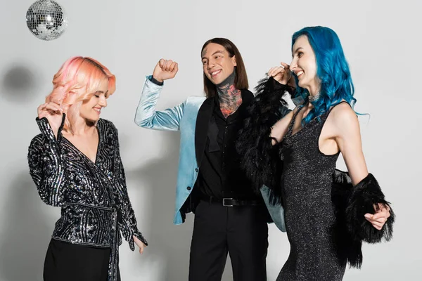 Joyful and elegant queer people celebrating christmas and dancing on grey background — Stock Photo