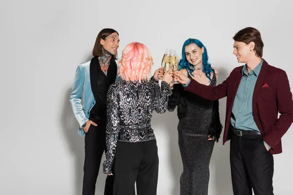 Pessoas não binárias alegres e elegantes brindar com champanhe durante a festa de ano novo em fundo cinza — Stock Photo