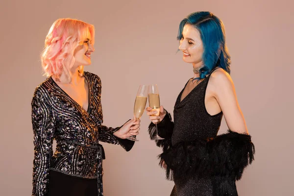 Amis queer joyeux en vêtements de fête cliquetis verres à champagne pendant la fête de Noël sur fond beige — Photo de stock