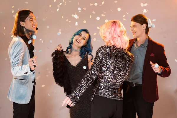 Gente queer emocionada en ropa festiva bailando durante la fiesta de Navidad sobre fondo beige - foto de stock