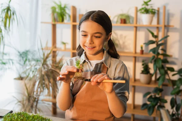 Felice preteen ragazza che tiene pianta microverde e pala a casa — Foto stock