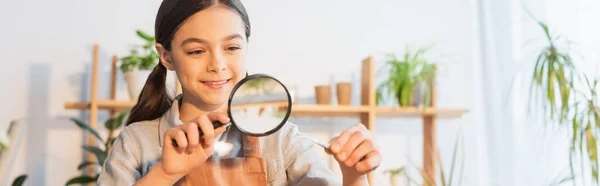 Fröhliches Kind hält Pinzette mit Pflanze und Lupe zu Hause, Banner — Stockfoto