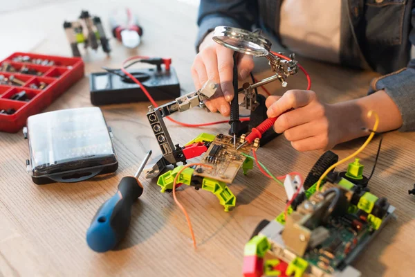 Vue recadrée de garçon faisant modèle robotique avec millimètre près de tournevis à la maison — Photo de stock