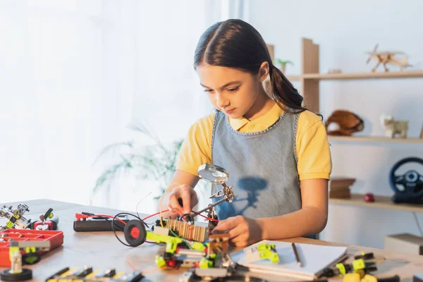 Preteen child modeling robotic model near notebook on table — Stock Photo