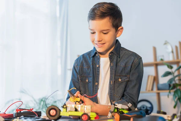 Preteen boy with pliers assembling robotics model on table at home — Stock Photo