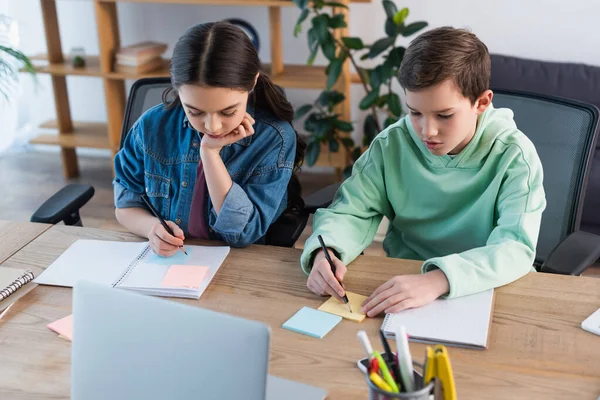 High angle view of preteen friends doing homework near laptop at home — Stock Photo