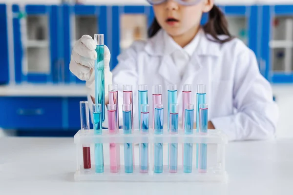 Vista recortada de chica borrosa en guante de látex sosteniendo tubo de ensayo en laboratorio - foto de stock