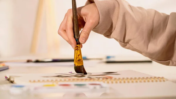 Cropped view of woman painting near blurred watercolor paint at home — Stock Photo
