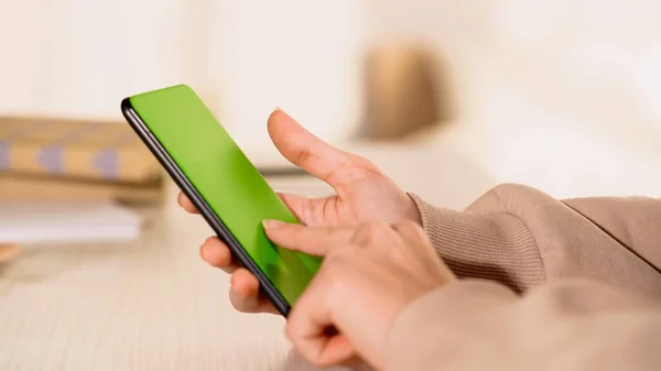 Ausgeschnittene Ansicht einer Frau, die zu Hause Mobiltelefon mit grünem Bildschirm benutzt — Stockfoto