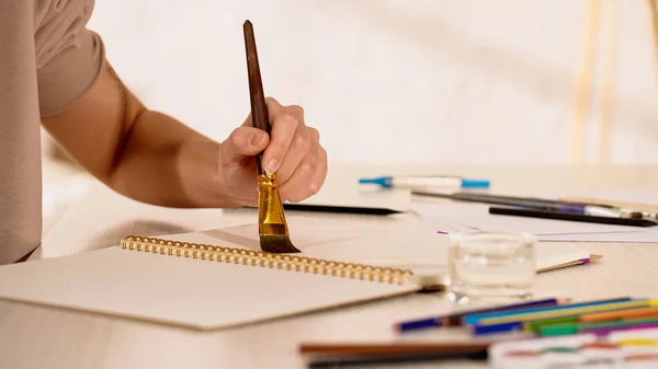 Vue recadrée de la peinture femme près de l'eau et des crayons de couleur flous à la maison — Photo de stock