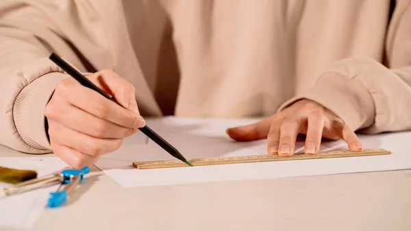 Cropped view of woman drawing with ruler and pencil near compass at home — Stock Photo