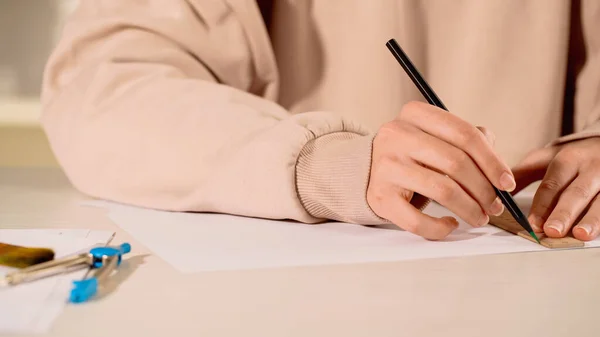 Cropped view of woman drawing with ruler on paper at home — Stock Photo