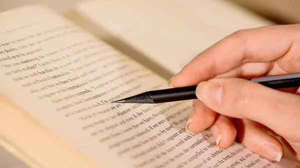 Vista cortada de mulher com desenho a lápis sobre livro — Fotografia de Stock