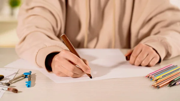 Ausgeschnittene Ansicht einer Frau, die mit Filzstift in der Nähe von Farbstiften zeichnet — Stockfoto