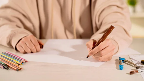 Vue recadrée d'une femme tenant un marqueur près du papier et des crayons de couleur — Photo de stock