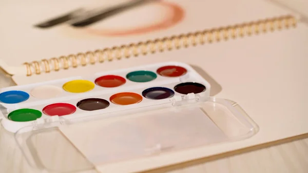 Close up view of watercolor paint on blurred sketchbook at home — Stock Photo