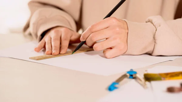 Vista cortada de mulher desenho com lápis e régua perto de bússola em casa — Fotografia de Stock