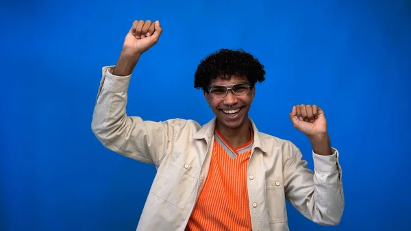 Homme afro-américain joyeux dans des lunettes montrant geste oui sur fond bleu — Photo de stock