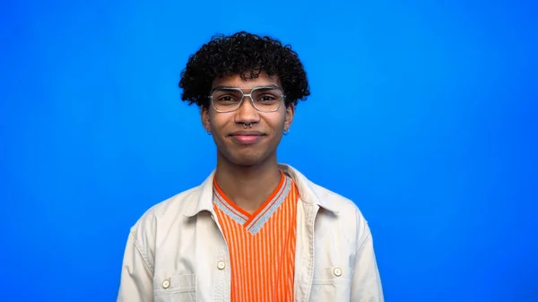 Стильний афроамериканець у окулярах дивиться на камеру, ізольовану на синьому — стокове фото