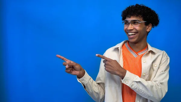 Elegante hombre afroamericano sonriendo y señalando con los dedos aislados en azul - foto de stock