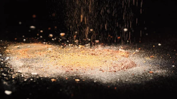 Close up view of crushed face powder pouring on black surface — Stock Photo