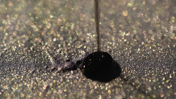 Vue rapprochée du liquide noir coulant sur une ombre à paupières brillante — Photo de stock