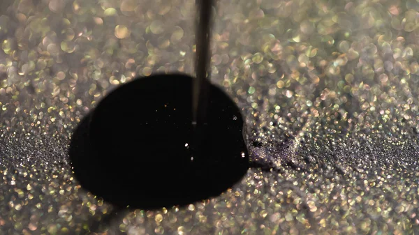 Close up view of nail polish pouring on sparkling eye shadow — Stock Photo