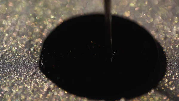 Close up view of black nail polish on sparkling glitter — Stock Photo