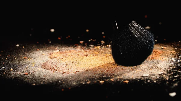 Vista de cerca del cepillo cosmético en polvo facial sobre fondo negro con iluminación - foto de stock