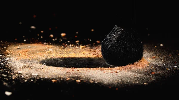 Vista de perto da escova cosmética e pó de rosto bege no fundo preto — Fotografia de Stock