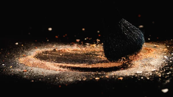 Cosmetic brush and face powder on black surface — Stock Photo