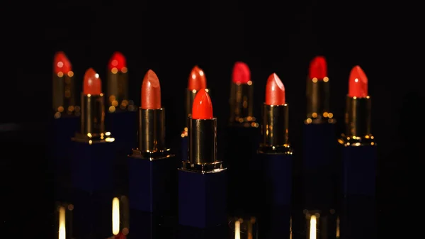 Vue rapprochée des rouges à lèvres rouge vif sur fond noir — Photo de stock