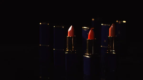 Rouge à lèvres rouge vif dans l'obscurité sur fond noir avec éclairage — Photo de stock