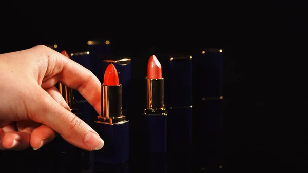 Cropped view of woman taking red lipstick on black background — Stock Photo