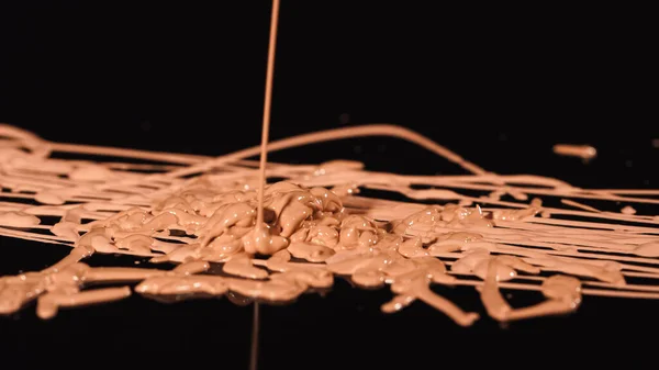 Close up view of beige makeup concealer pouring on black background — Stock Photo