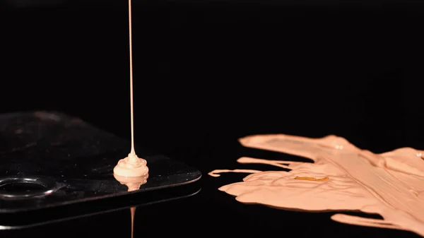 Close up view of makeup foundation pouring on palette on black background — Stock Photo