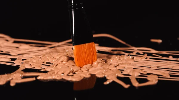 Close up view of synthetic cosmetic brush on makeup foundation on black background — Stock Photo