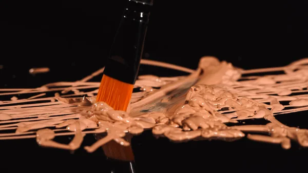 Close up view of cosmetic brush on makeup foundation on black background — Stock Photo