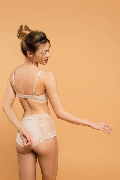 Vista posteriore della donna con pelle perfetta e corpo snello in posa in lingerie isolata sul beige — Foto stock