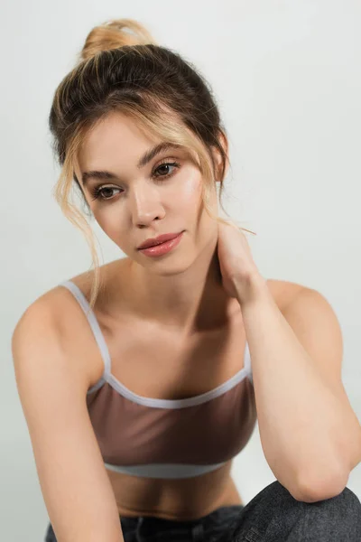 Retrato de mulher pensativa com maquiagem natural e pele perfeita tocando pescoço isolado em cinza — Fotografia de Stock