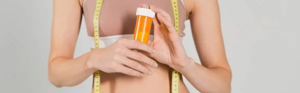Teilansicht einer fitten Frau mit Vitaminen und Maßband isoliert auf grau, Banner — Stockfoto
