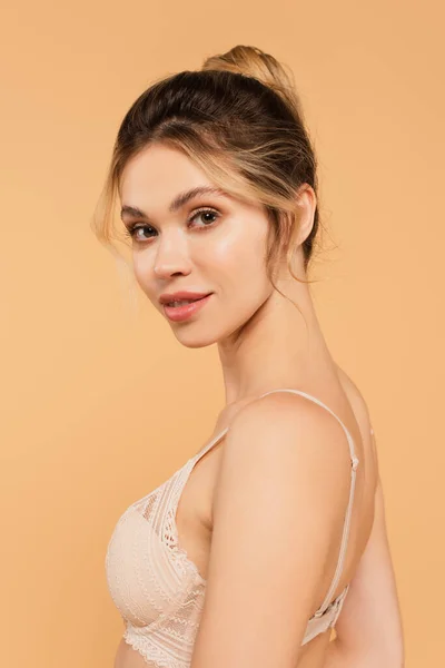 Portrait of young woman with natural makeup posing in lace bra isolated on beige — Stock Photo