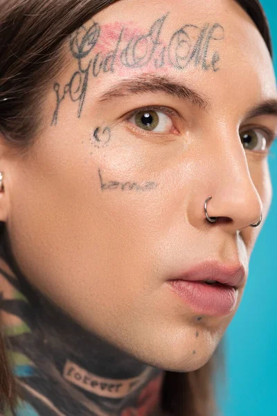 Close up de homem jovem e perfurado com tatuagens e pele lisa isolado em azul — Fotografia de Stock