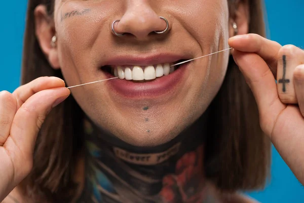 Vista ritagliata di allegro e tatuato uomo filo interdentale denti bianchi isolati su blu — Foto stock