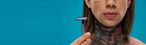 Cropped view of young man with tattoos holding safety razor isolated on blue — Stock Photo