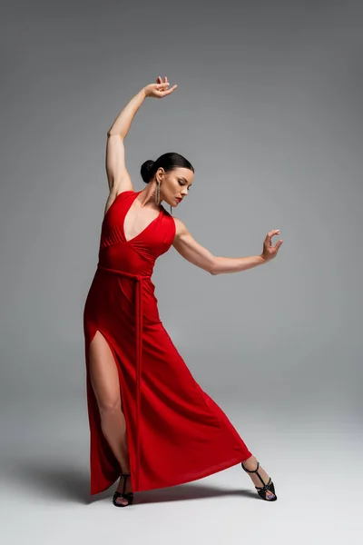 Woman in red dress and heels dancing on grey background — Stock Photo