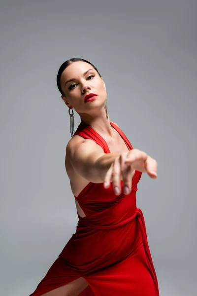 Bailarina en vestido rojo apuntando con el dedo a la cámara aislada en gris - foto de stock