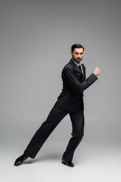 Professional dancer in suit performing tango on grey background — Stock Photo