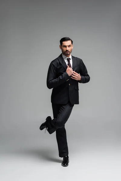 Elegante bailarina de salón ajustando chaqueta mientras realiza tango sobre fondo gris - foto de stock